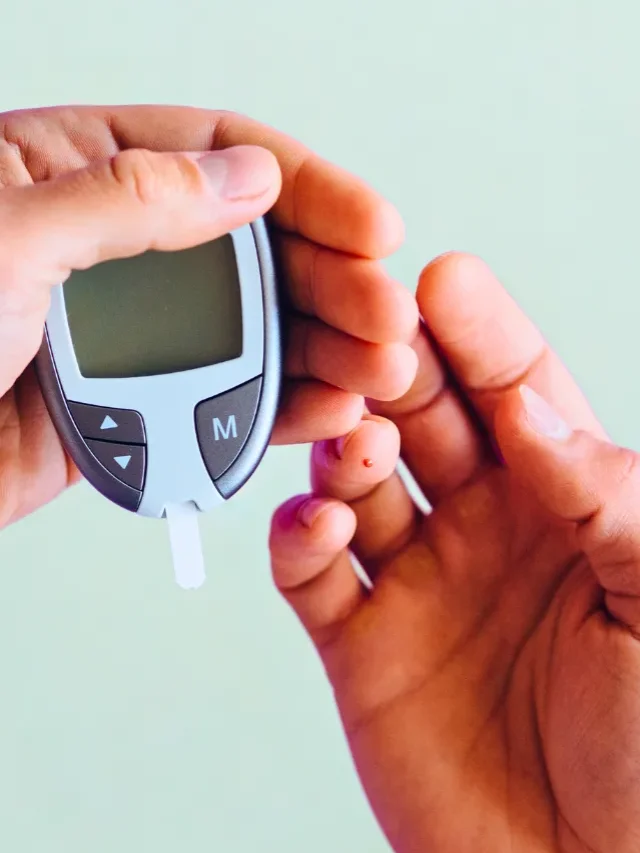 An image of male hand holding blood sugar measuring machine and measruing blood sugar level